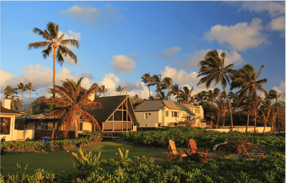A well-groomed backyard in Hawaii at sunset. Three residences and palm trees are seen in background. ATTYX Roofing
