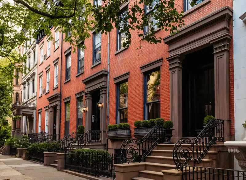 A street view of red brick townhomes in New York City during summer. ATTYX Roofing