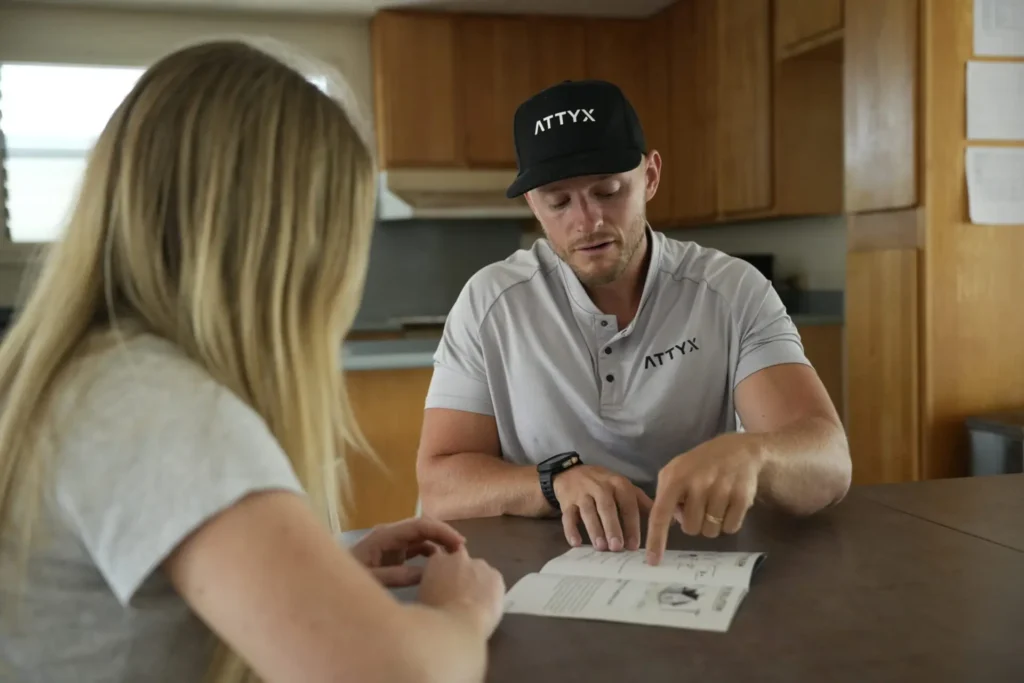 Salesman explaining the benefits of ATTYX with a potential customer in her home. ATTYX Roofing and Solar