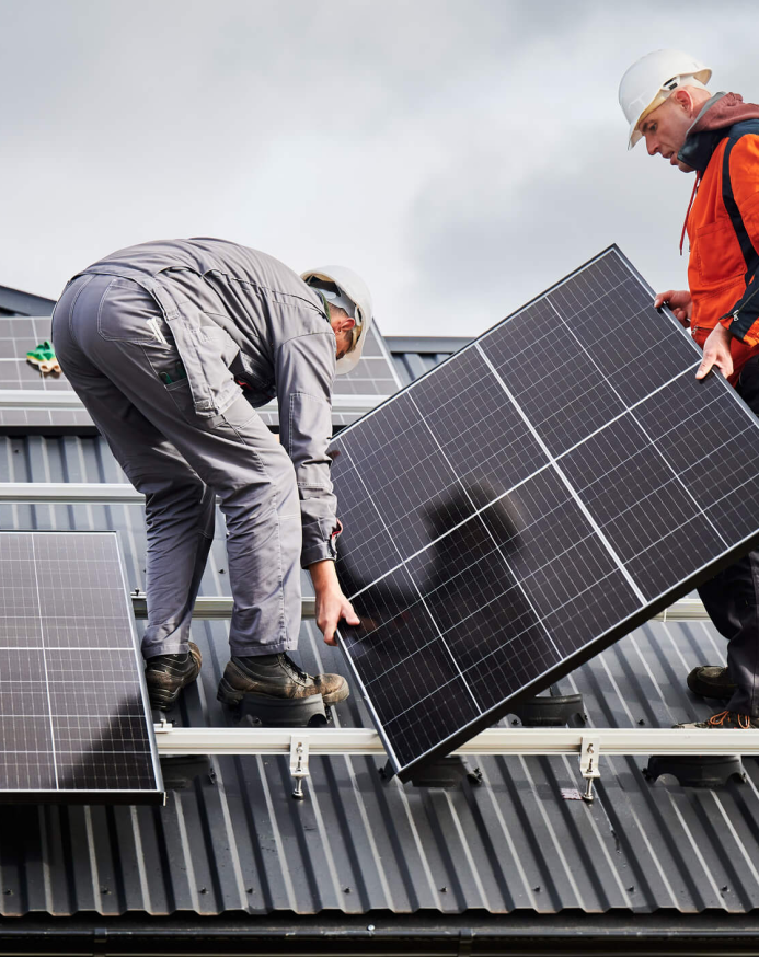 Two solar technicians installing solar panels on the roof of a home.